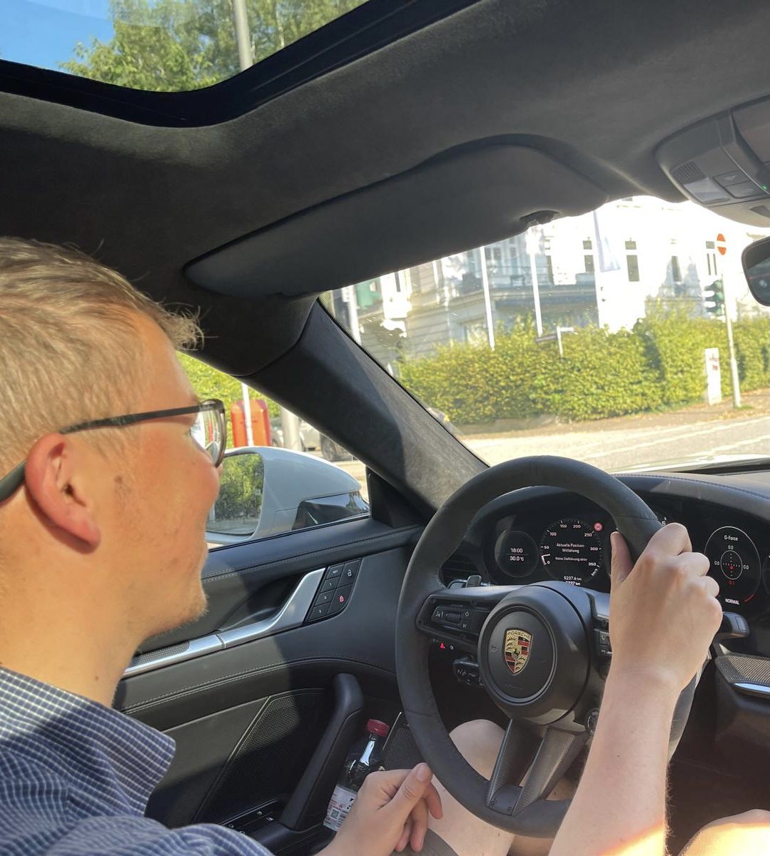 Johannes behind the wheel of a Porsche