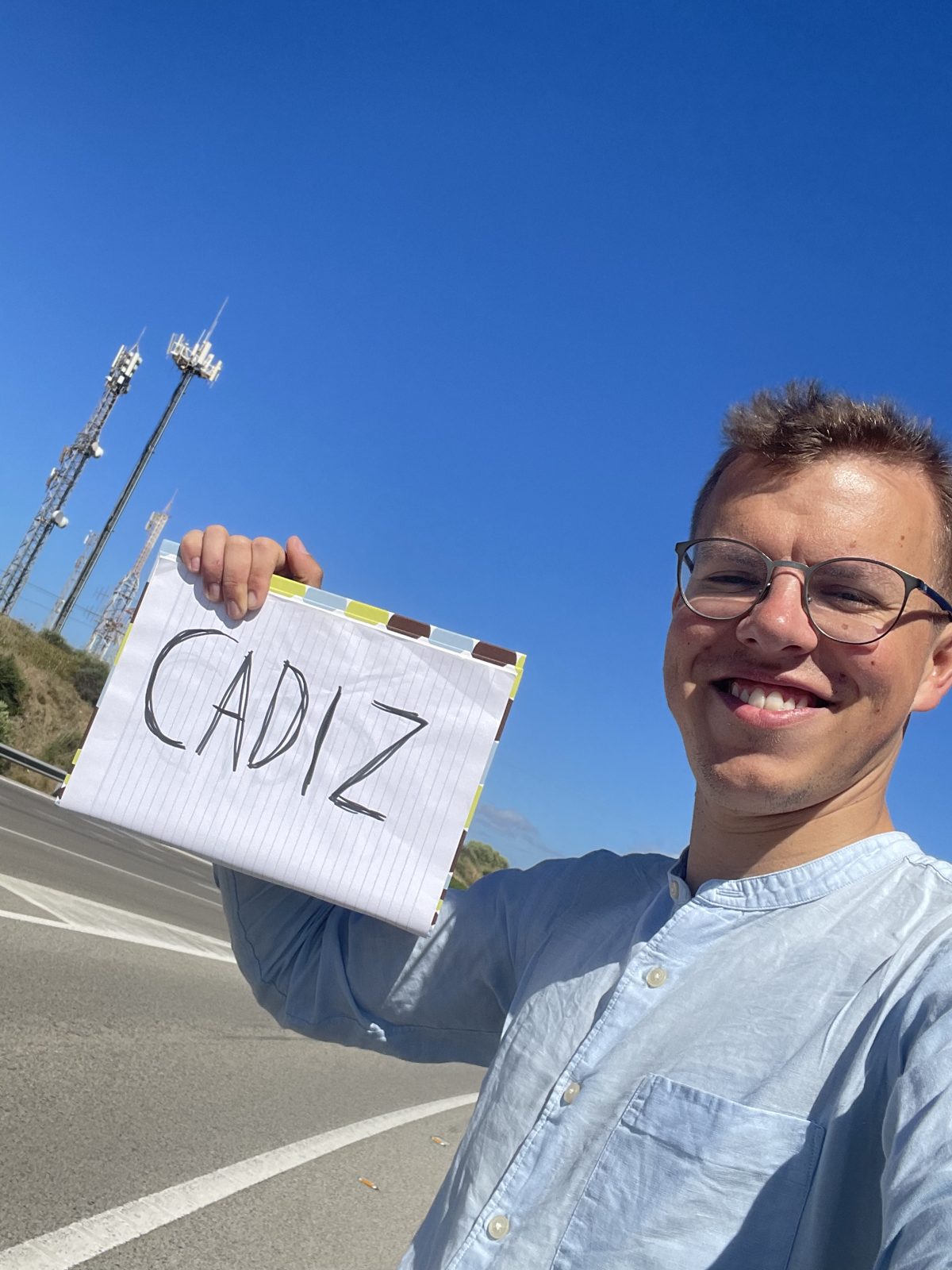 Selfie of Johannes holding an A4 spiral notebook with CADIZ written on it, at the side of a road